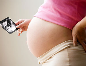 pancione di una donna incinta e mano che tiene l'ecografia