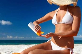 donna in spiaggia che mette crema solare